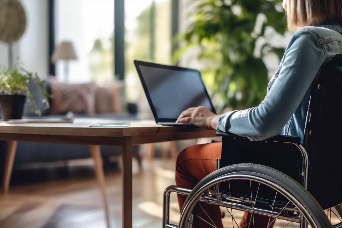 Persona con discapacidad en silla de ruedas trabajando frente a un ordenador