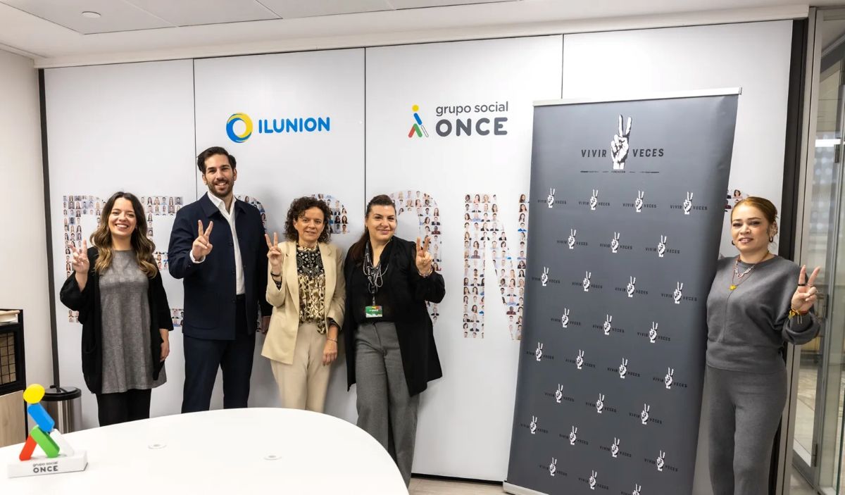 Foto de familia del acuerdo de Ilunion con la Fundación Vivir dos Veces  haciendo el gesto de la V con los dedos