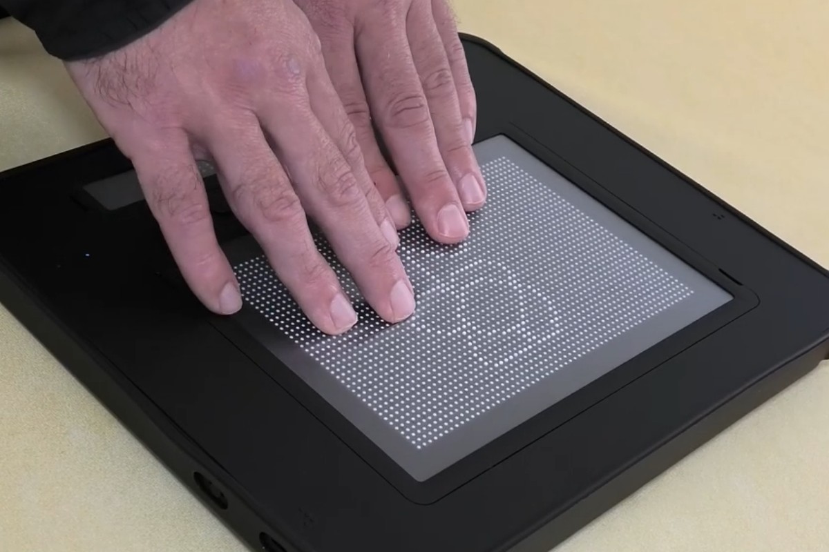 Unas manos tocan una imagen en braille que reproduce el dibujo de una flor