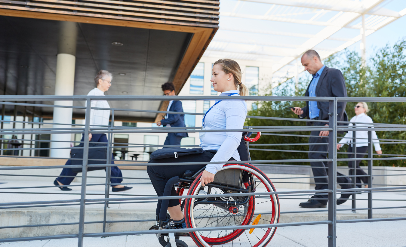 Joven en silla de ruedas por una rampa de acceso a un edificio