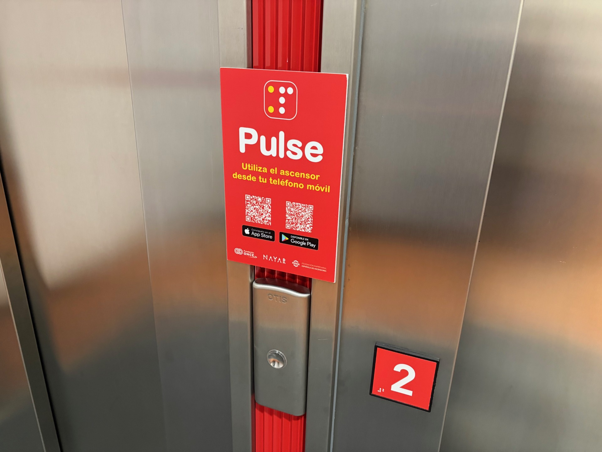 Cartela con información del manejo de la app PULSE a través de un código QR en un ascensor