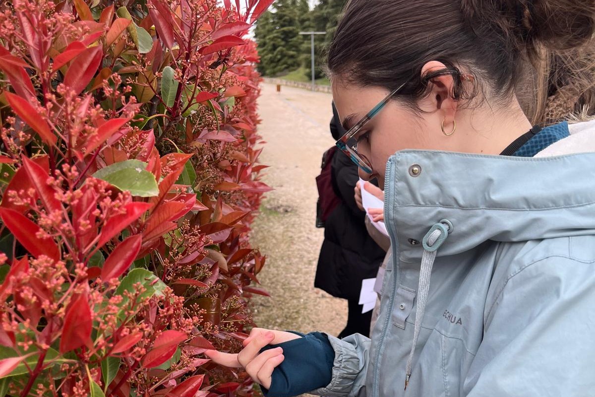 Una de las jóvenes participantes toca una de las plantas en la visita al Jardín Botánico de Madrid previstas en el Campus