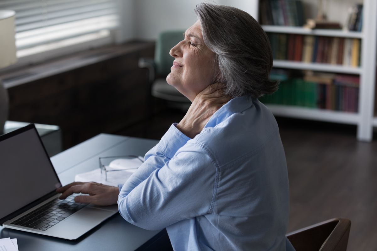 Mujer de mediana edad realizando una gesto de dolor en el cuello