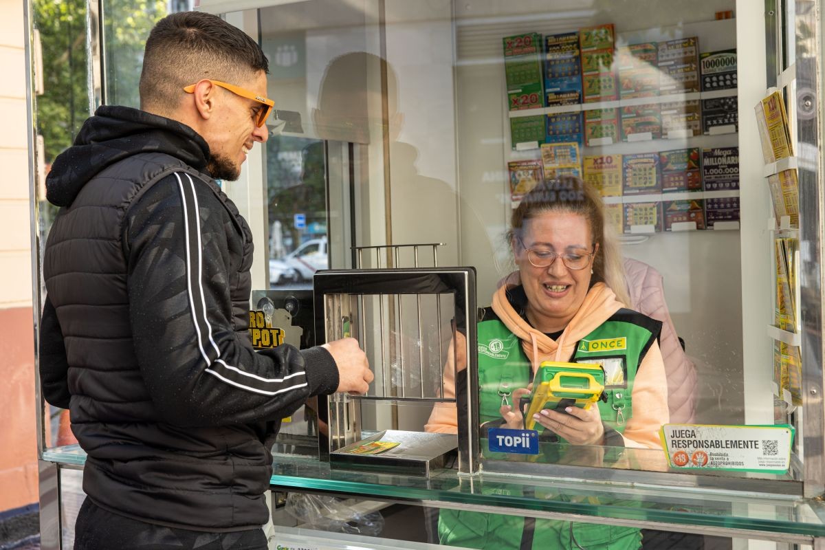 Vendedora de la ONCE atendiendo a un cliente en su kiosco