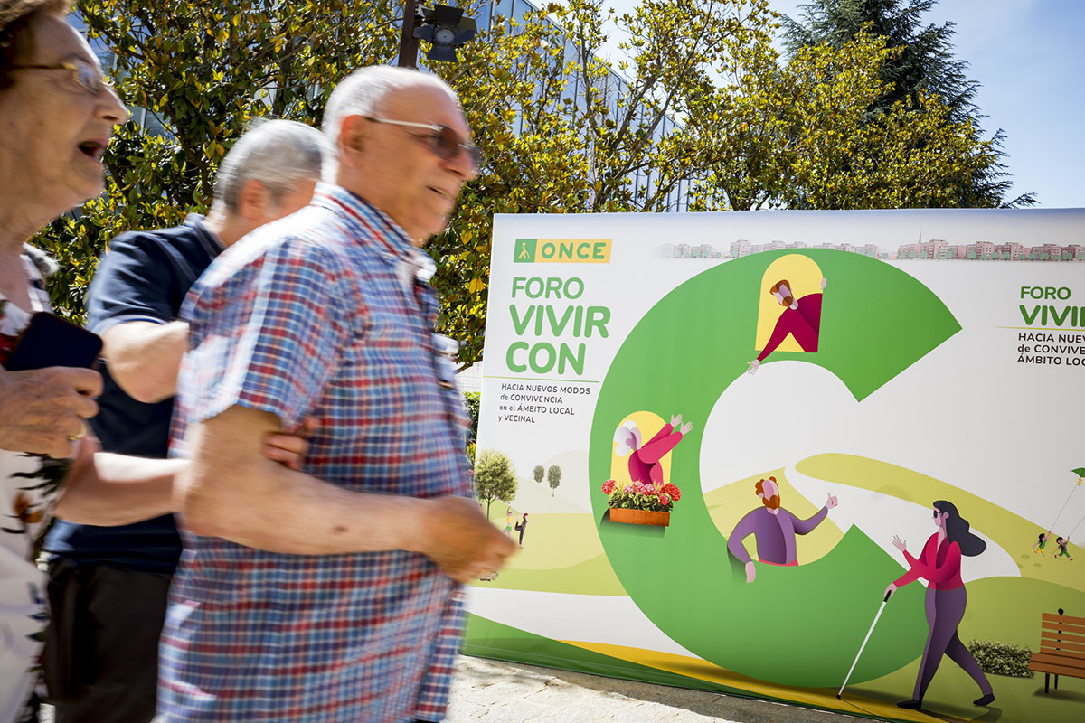 Primer plano del cartel del Foro Vivir con C, con asistentes llegando