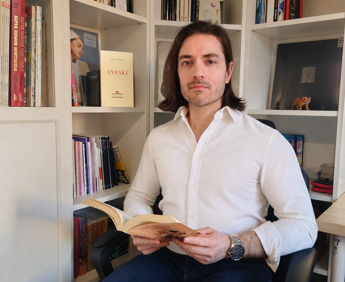 Pedro Cepedal sostiene un libro mientras posa en su biblioteca personal 