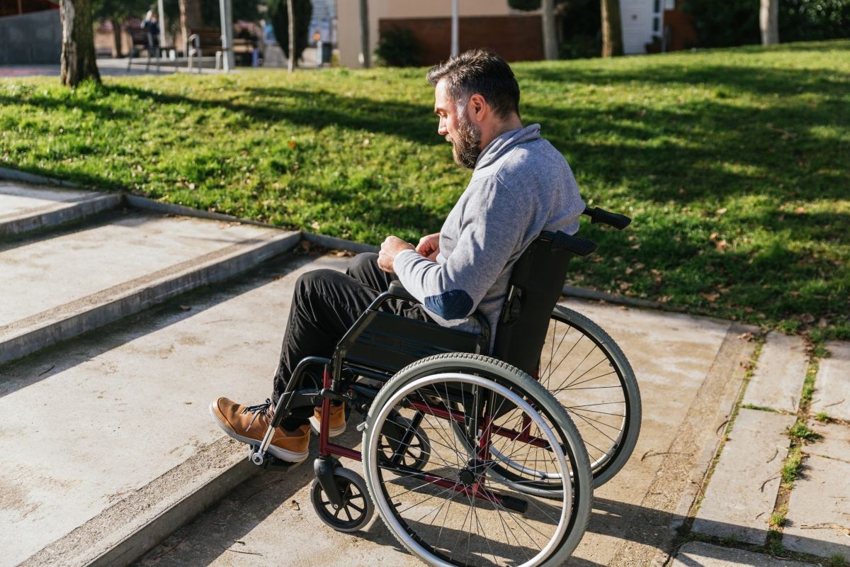 Hombre en silla de ruedas frente a una escalera
