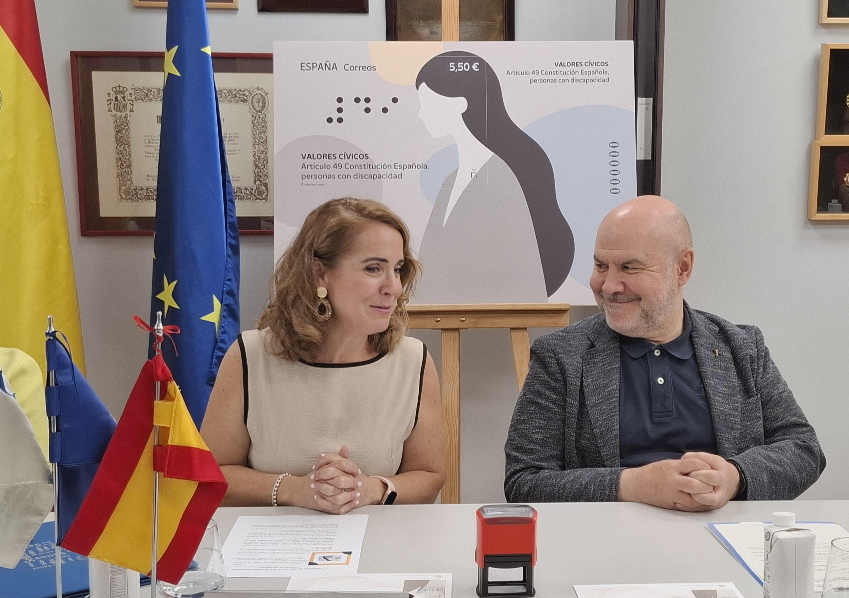 Nuria Lera Hervás y Luis Cayo Pérez con el cartel de la reproducción del sello conmemorativo del artículo 49 de la Constitución