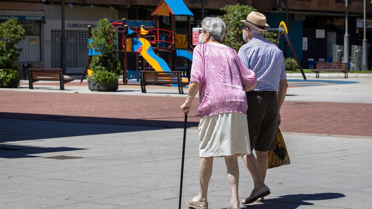 Dos personas mayores, una de ellas con un bastón, caminando por la calle