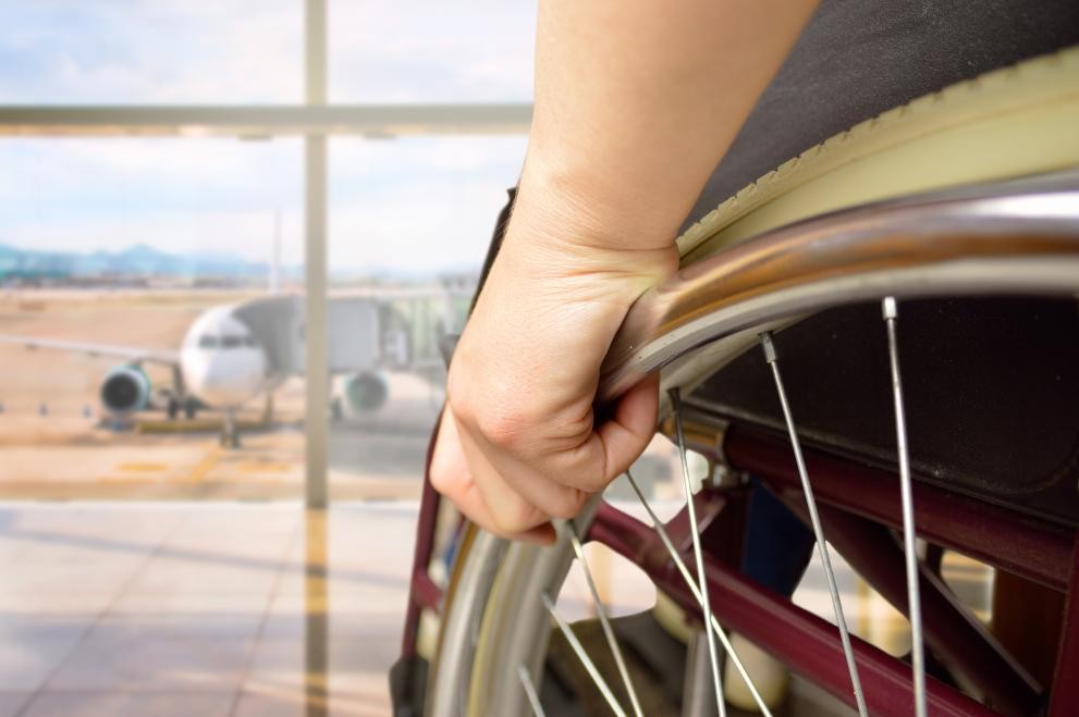 Primer plano de silla de ruedas ante un avión en un aeropuerto