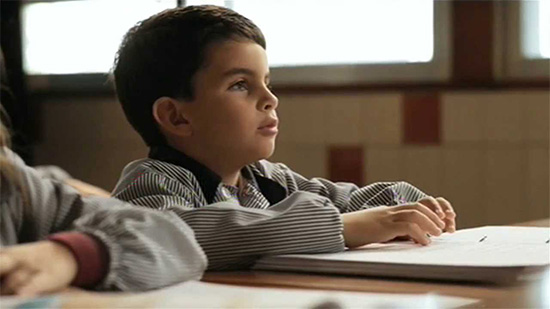 Un niño ciego total estudiando en su pupitre en el aula y con sus apuntes en braille