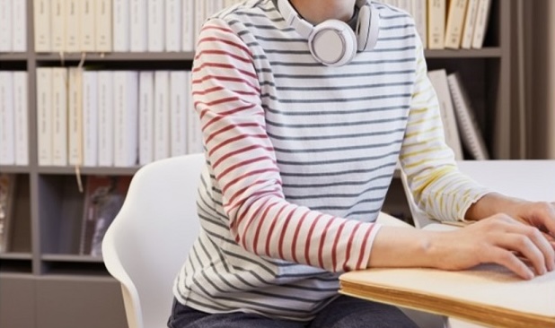 Unas manos de chica joven leyendo braille, auriculares en el cuello