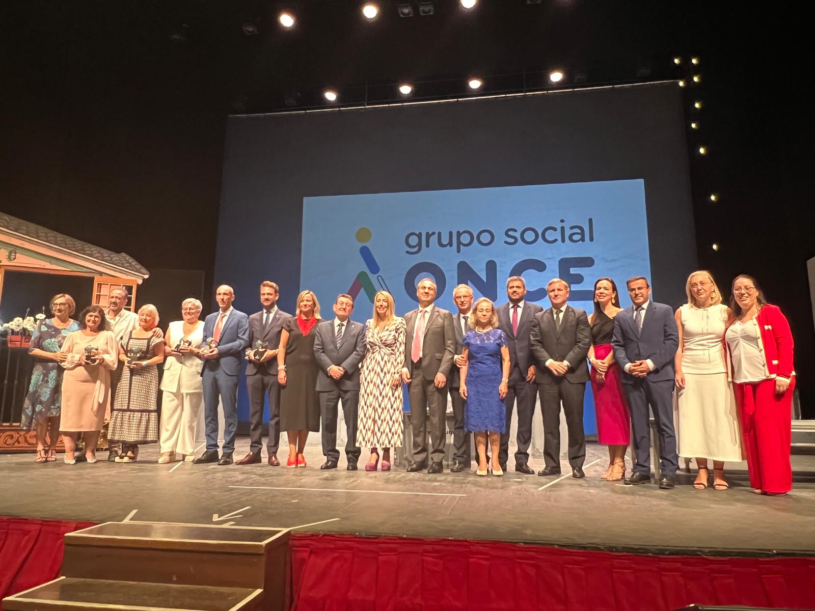 Foto de familia sobre el escenario con gran logo del Grupo Social ONCE al fondo