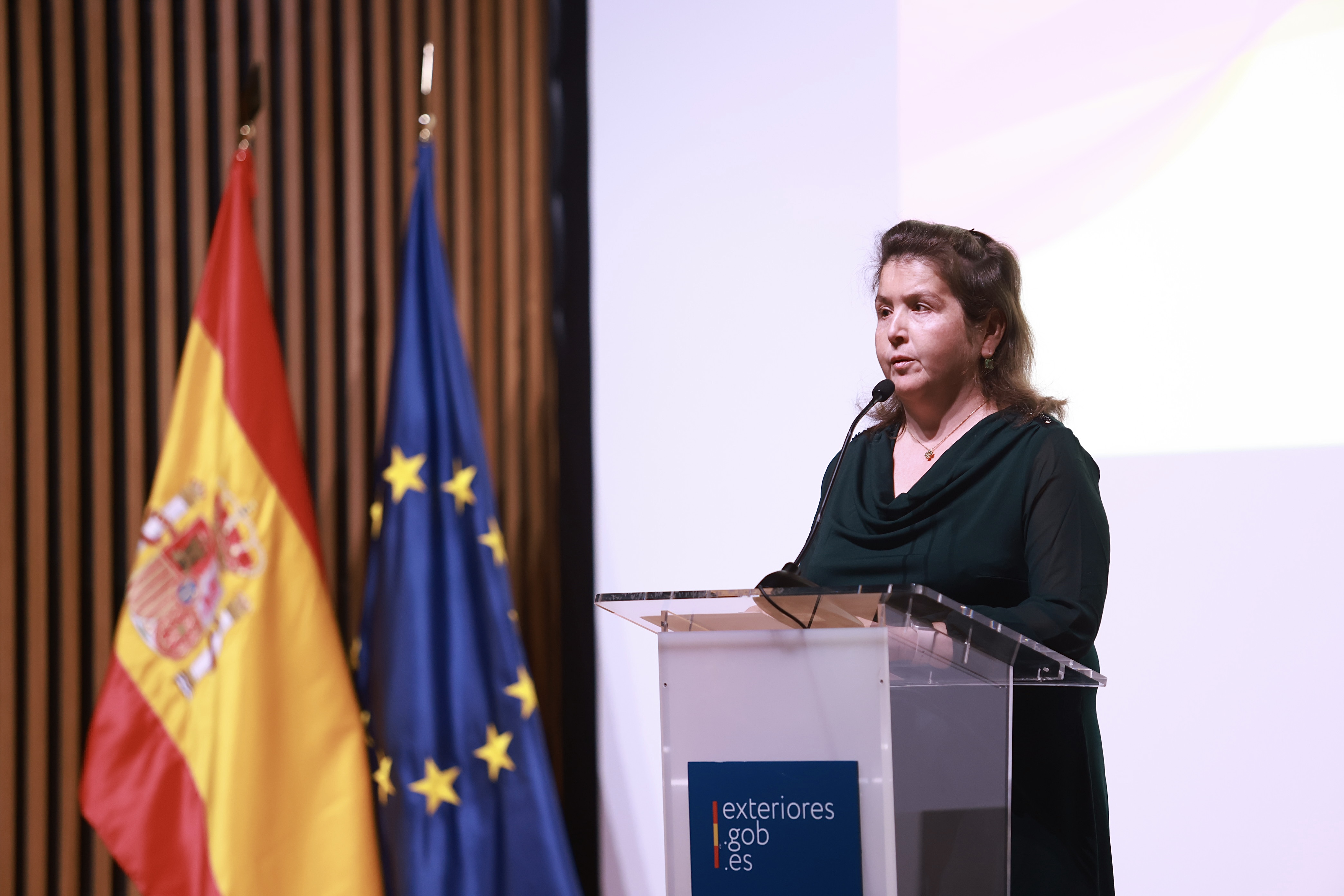 Bárbara Palau en el atril con bandera española y europea a su lado.