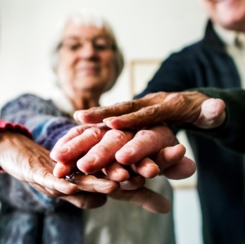 Dos personas ancianas juntando las manos en el centro de la imagen