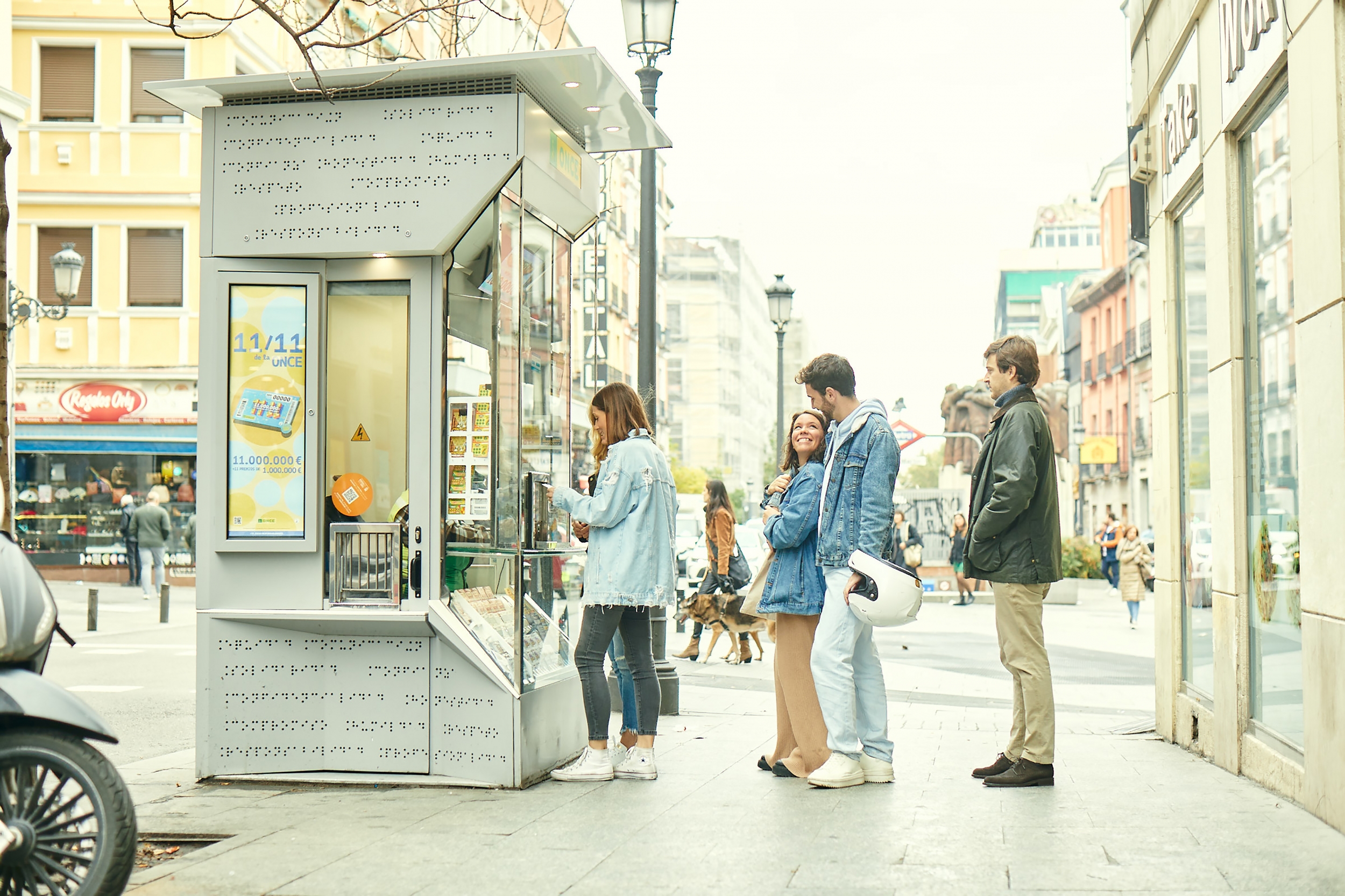 Foto de un kiosco de la ONCE con una fila de personas esperando para comprar