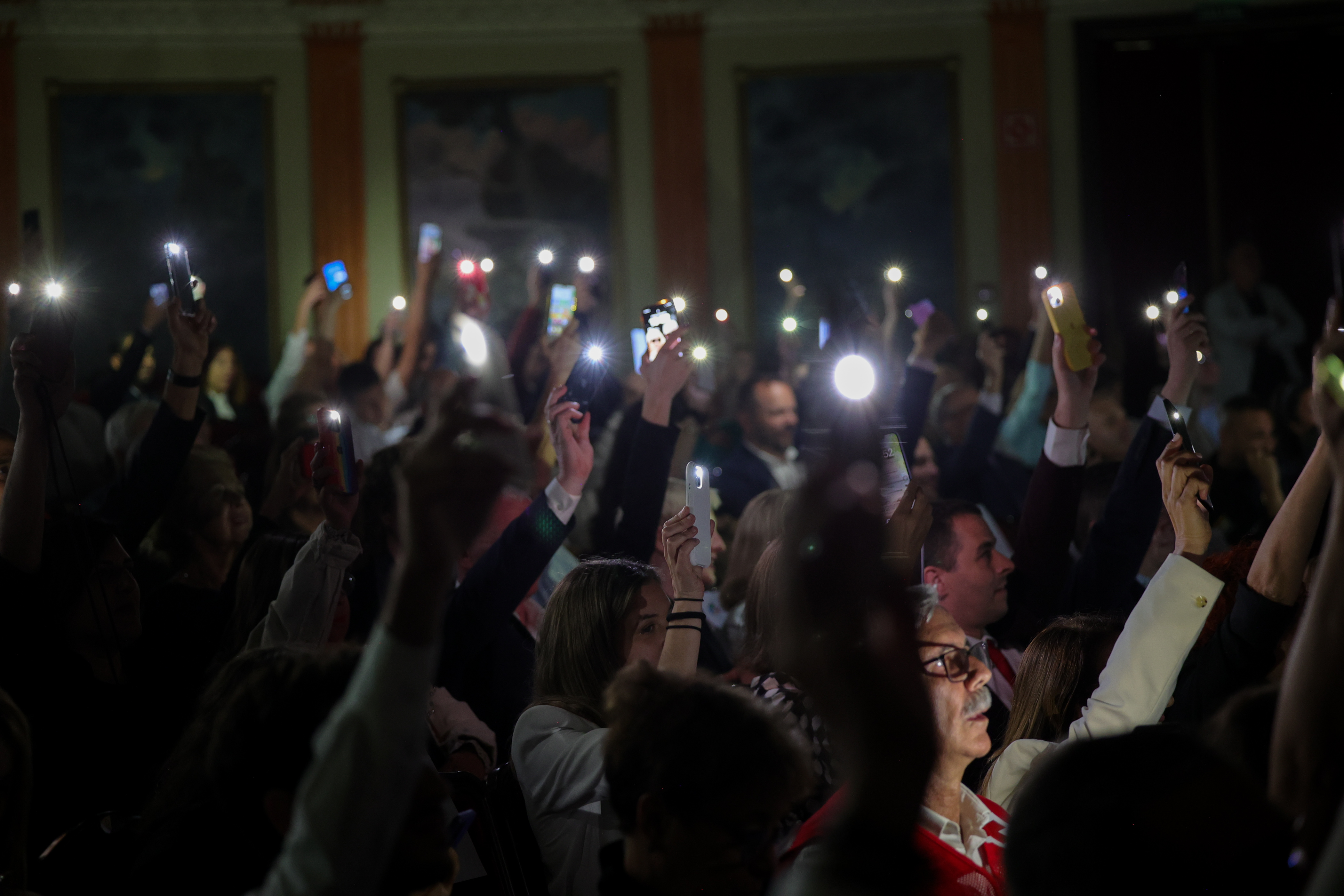 Linternas de los móviles del público encendidas en un auditorio oscuro
