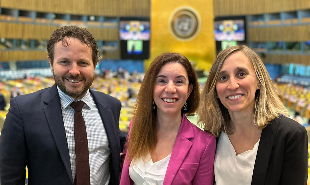Retrato de un hombre y dos mujeres con la cámara de la ONU desenfocada al fondo
