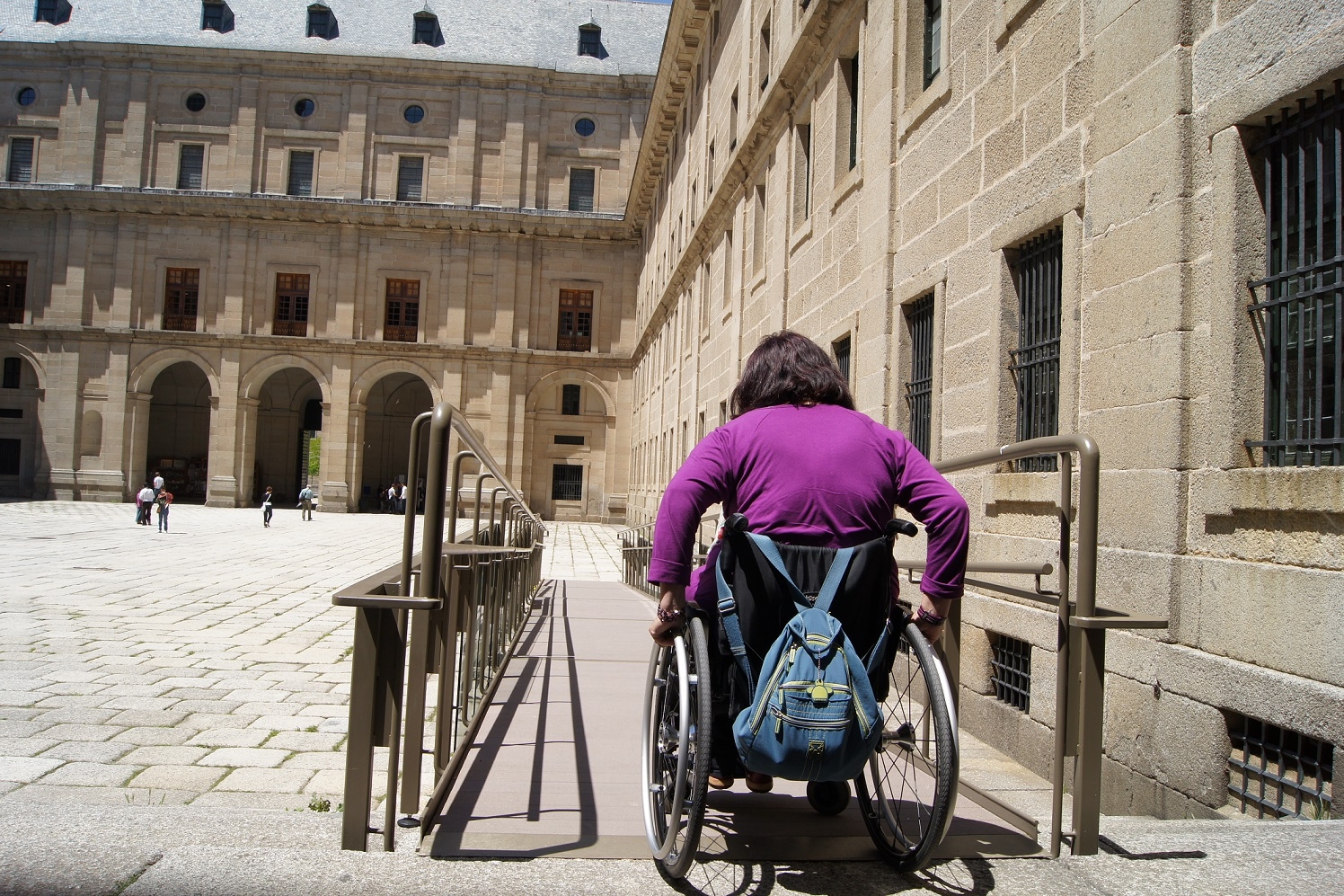 Mujer en silla de ruedas bajando una rampa