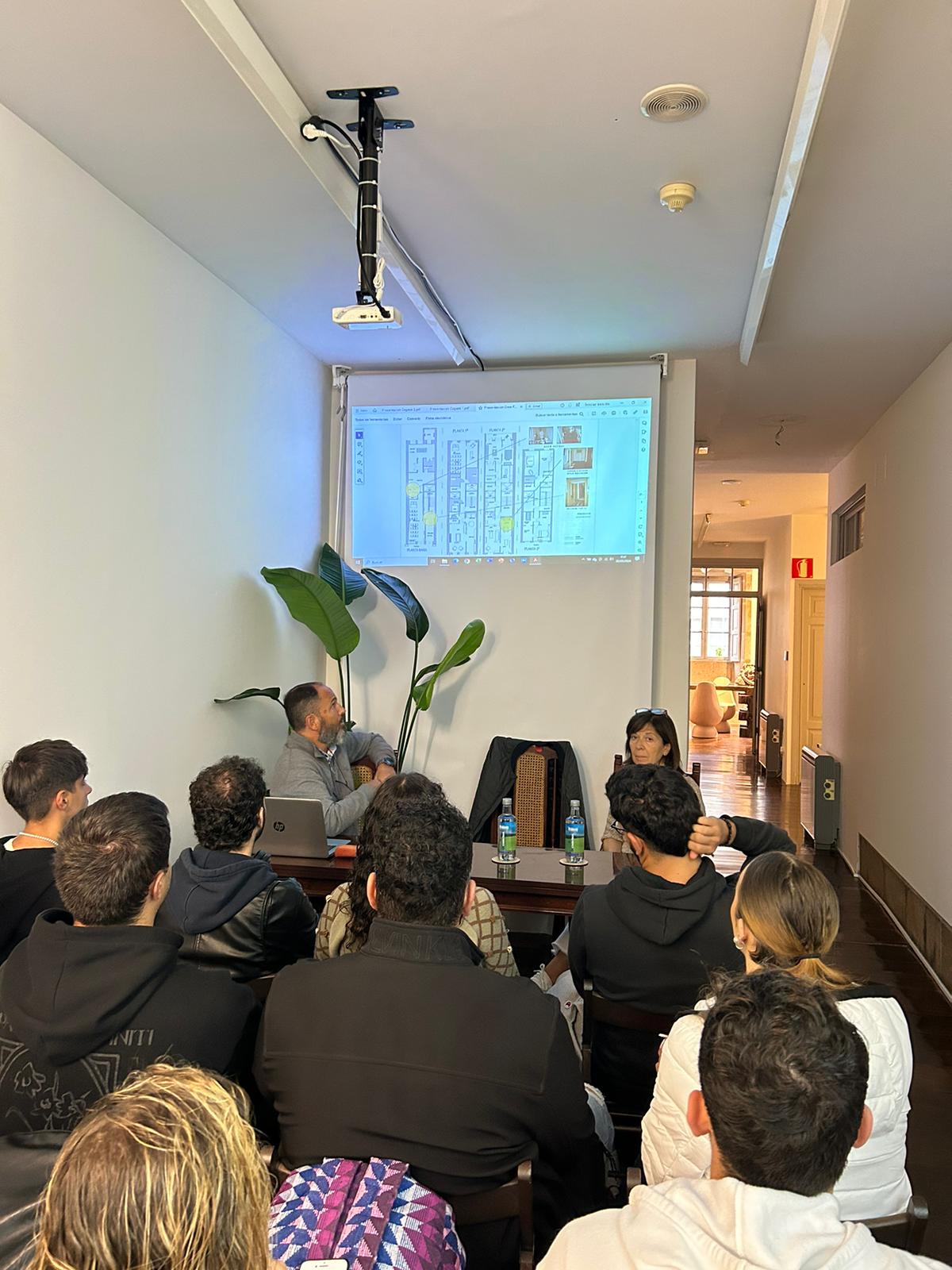 Foto de la charla con Diego y Laura, en las que se ve a los asistentes atentos a la explicación proyectada sobre planos de vivienda y accesibilidad. El espacio era íntimo, lo que favoreció una conversación cercana y participativa.