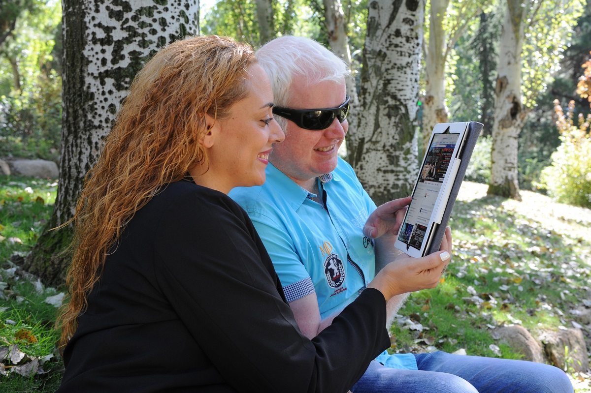 Una pareja joven, consultando una tablet en un parque.