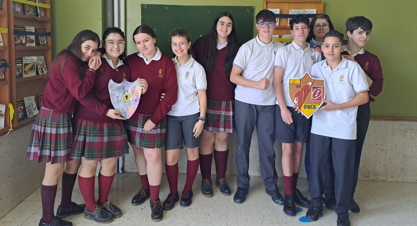 Coral junto a su grupo de alumnos y alumnas mostrando los escudos que han presentado al concurso