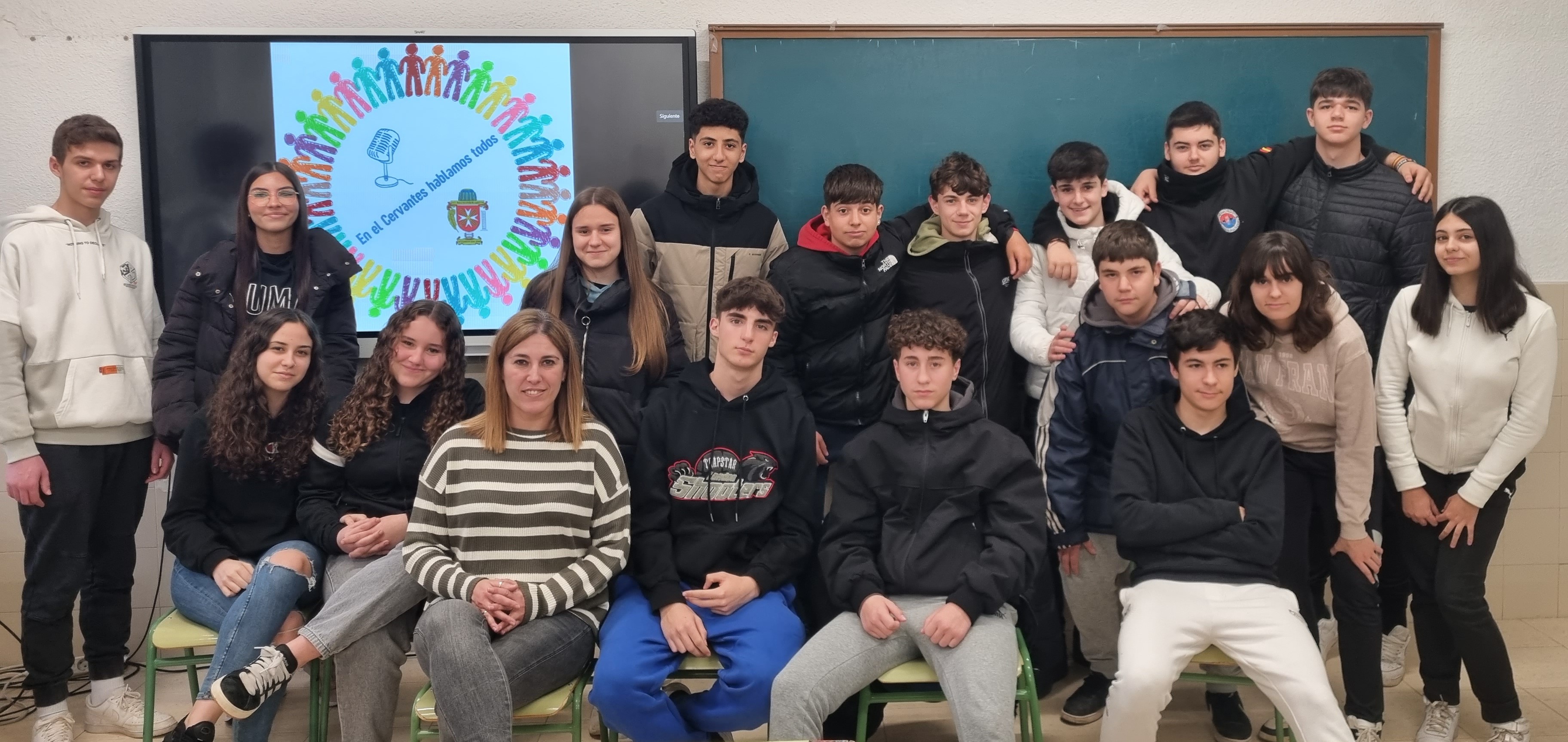 Sandra, sentada en primera línea, junto al grupo participantes con la imagen de su escudo al fondo