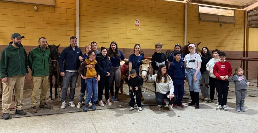 Grupo de niños y niñas afiliadas junto a monitores y responsables en el centro ecuestre