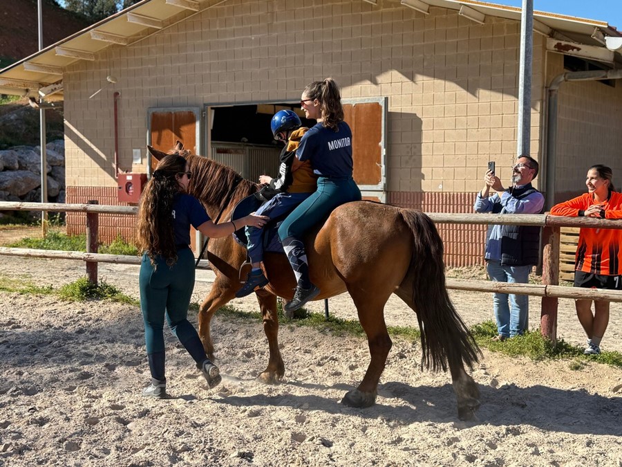 Uno de los niños junto a la monitora ecuestre durante la monta del caballo