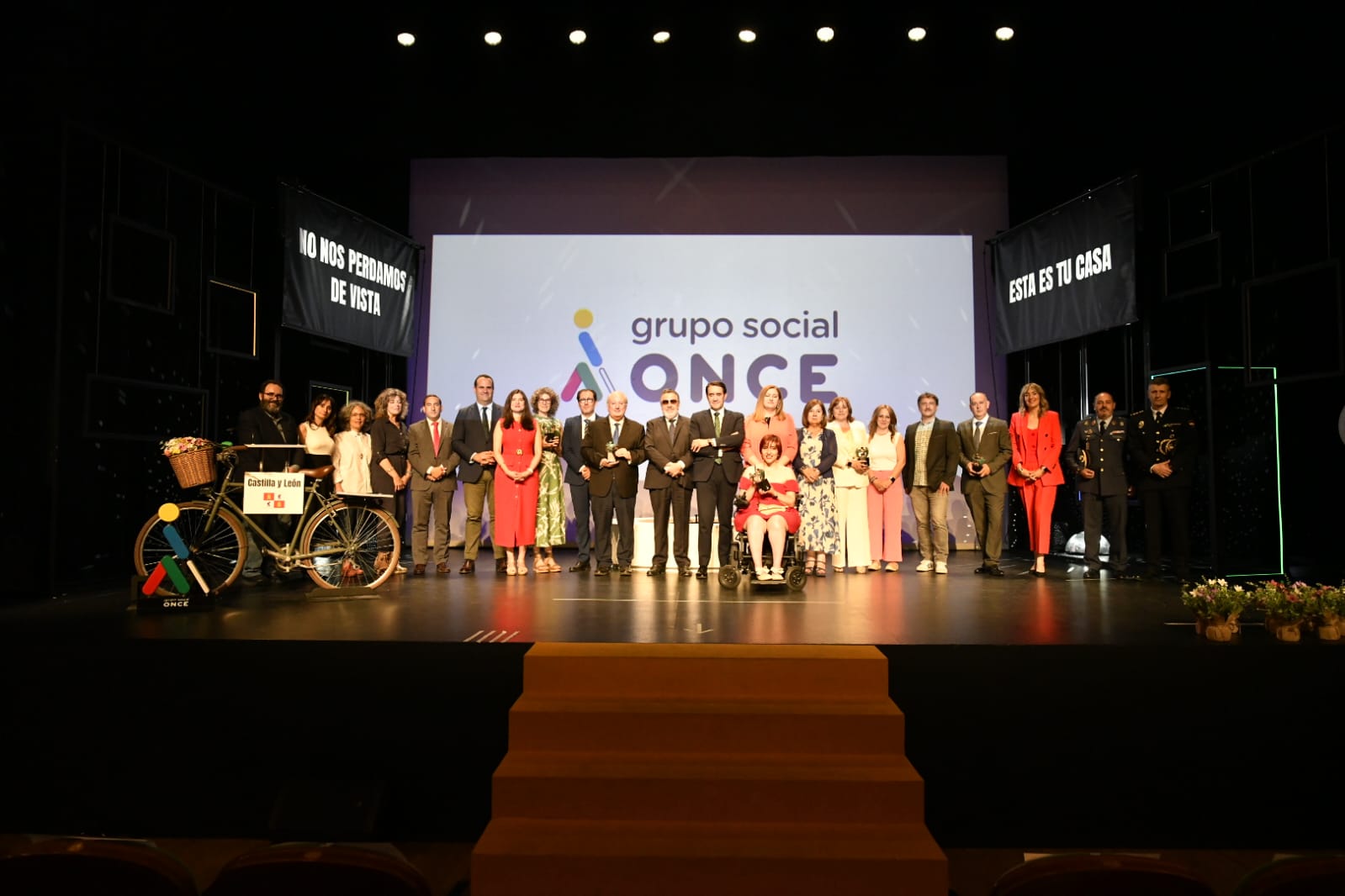 Foto de familia de todos los premiados sobre el escenario, una bicicleta-atril a la derecha y logo del Grupo Social ONCE en pantalla trasera