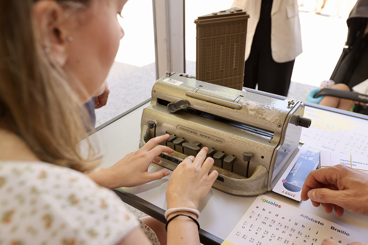 Una visitante escribe con la máquina Perkins