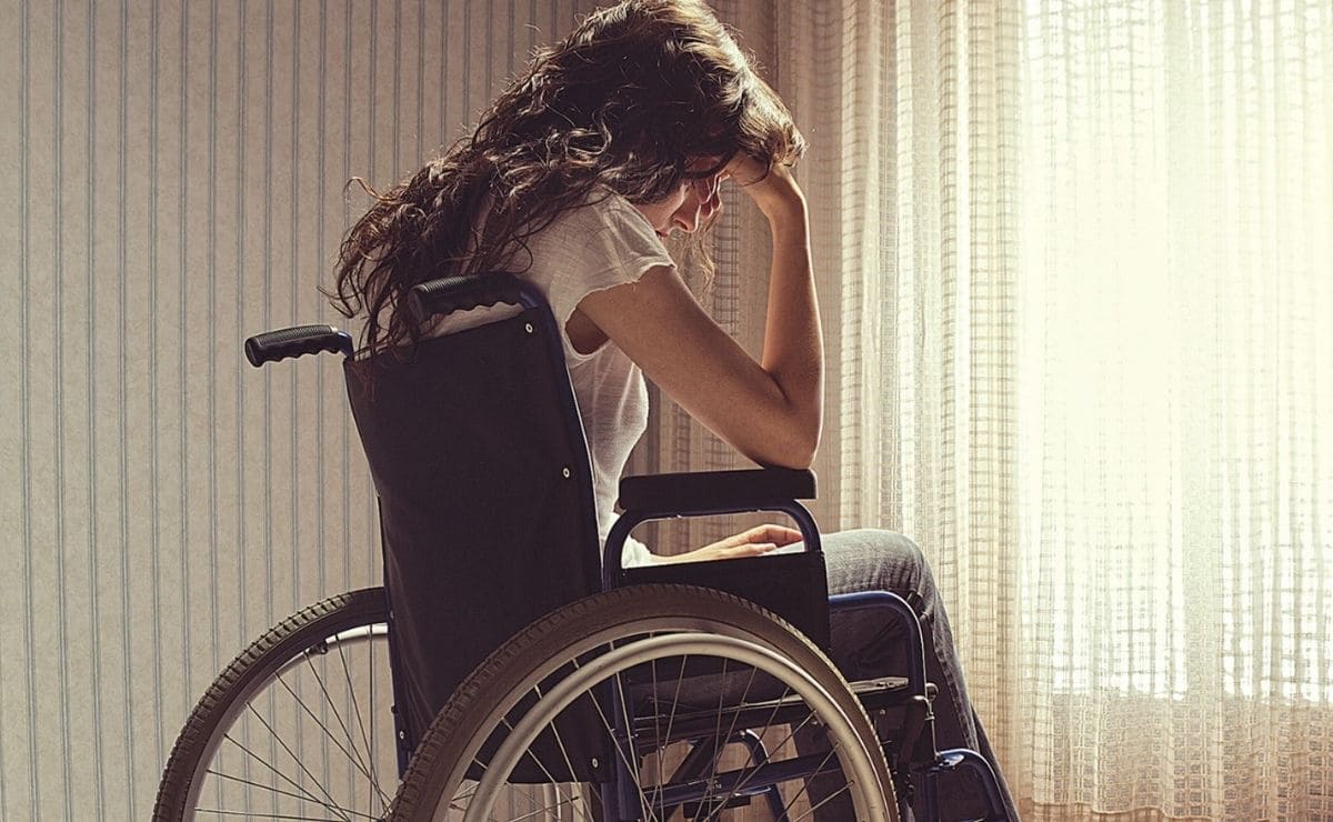 Joven con discapacidad en silla de ruedas cabizbaja Joven con discapacidad en silla de ruedas cabizbaja