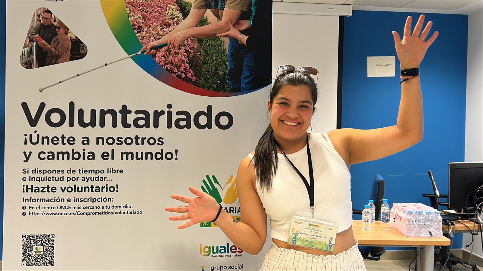 Cindy junto al cartel de las jornadas anima a otros jóvenes a participar en algunos de los programas de voluntariado de la ONCE