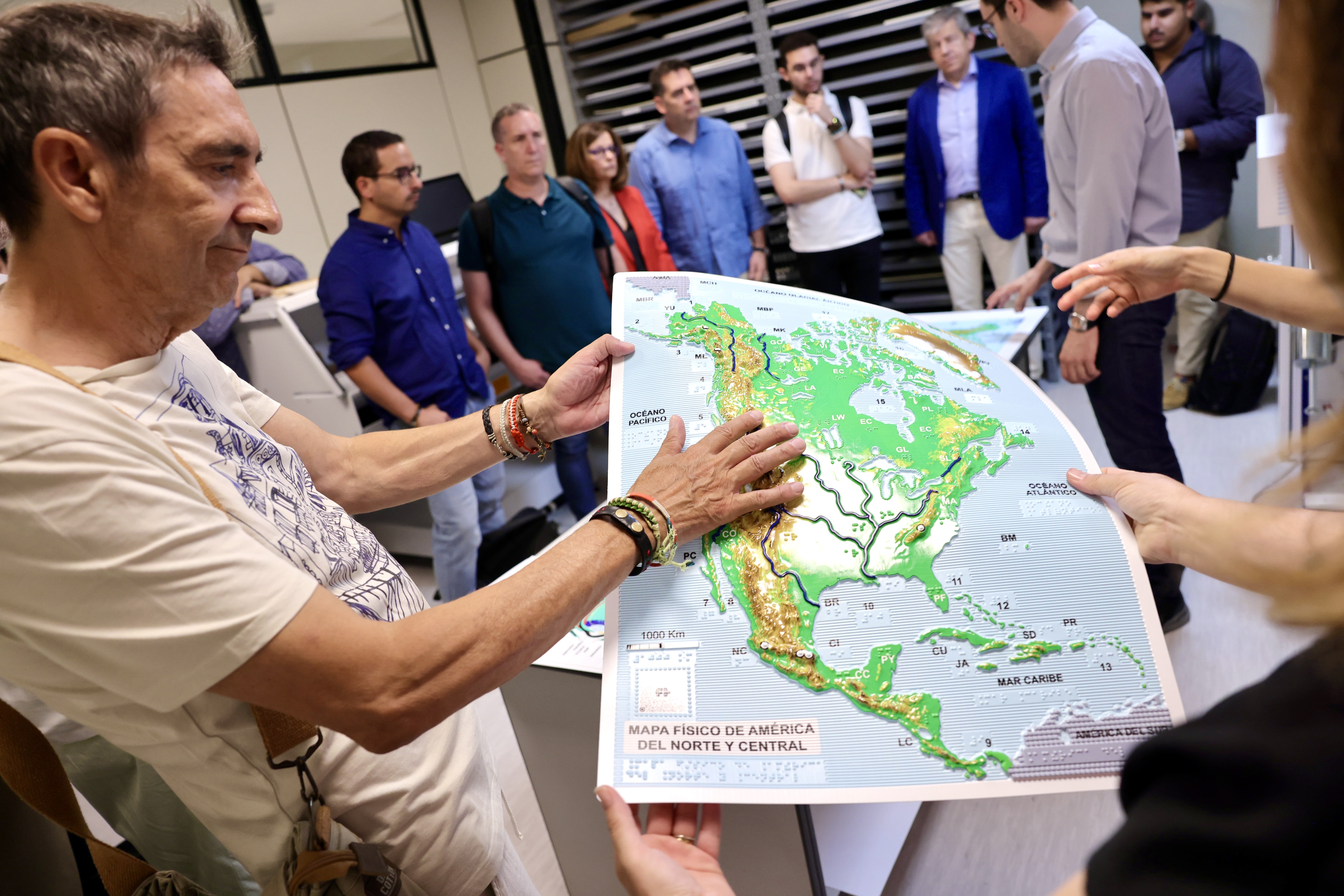 Uno de los miembros de los jurados toca un mapa en relieve producido en el SBO