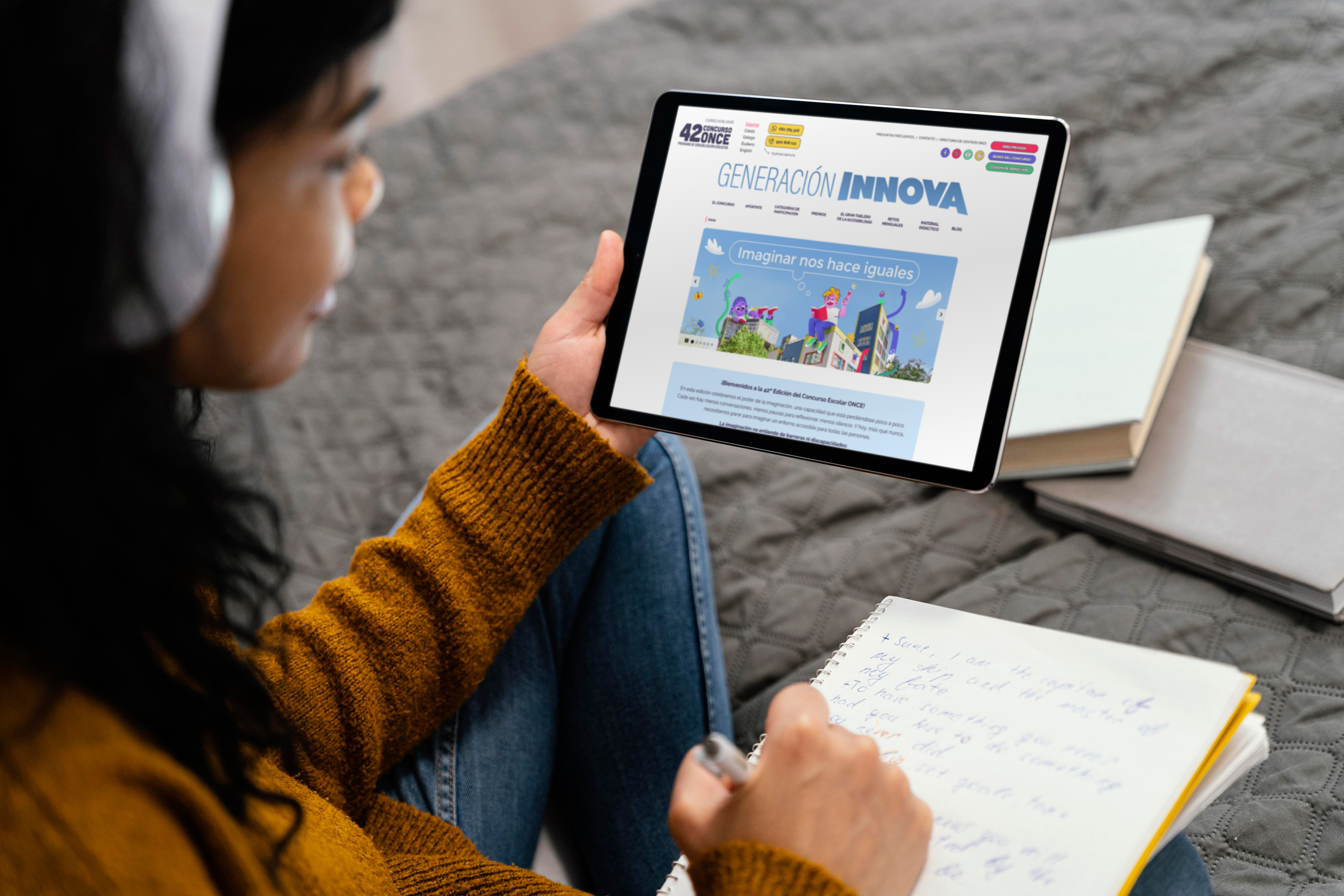 Una joven visualizando una tablet con la imagen de la web del 42 Concurso Escolar ONCE