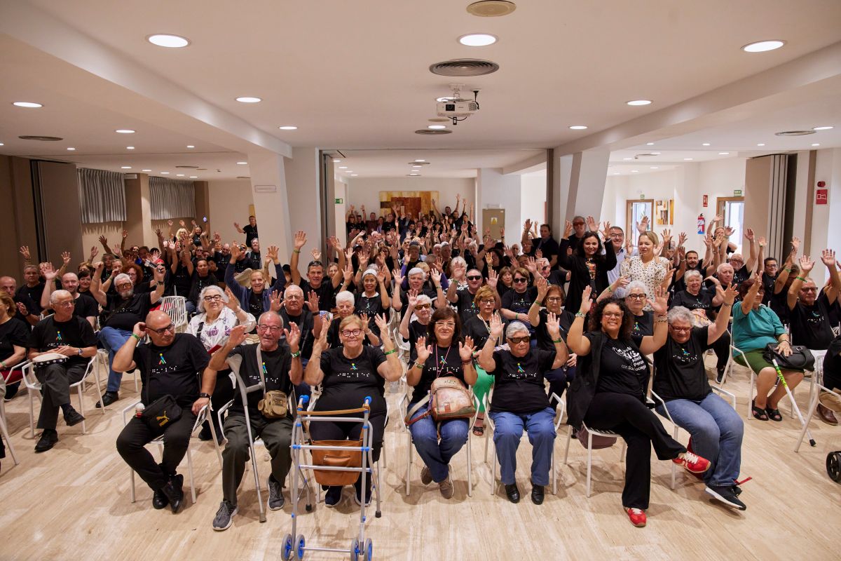 Vista panorámica de todos los participantes en el turno de vacaciones junto a sus monitores y responsables de la ONCE, Ana Díaz, Andrés Ramos y Ana Esteban, saludando levantando las manos