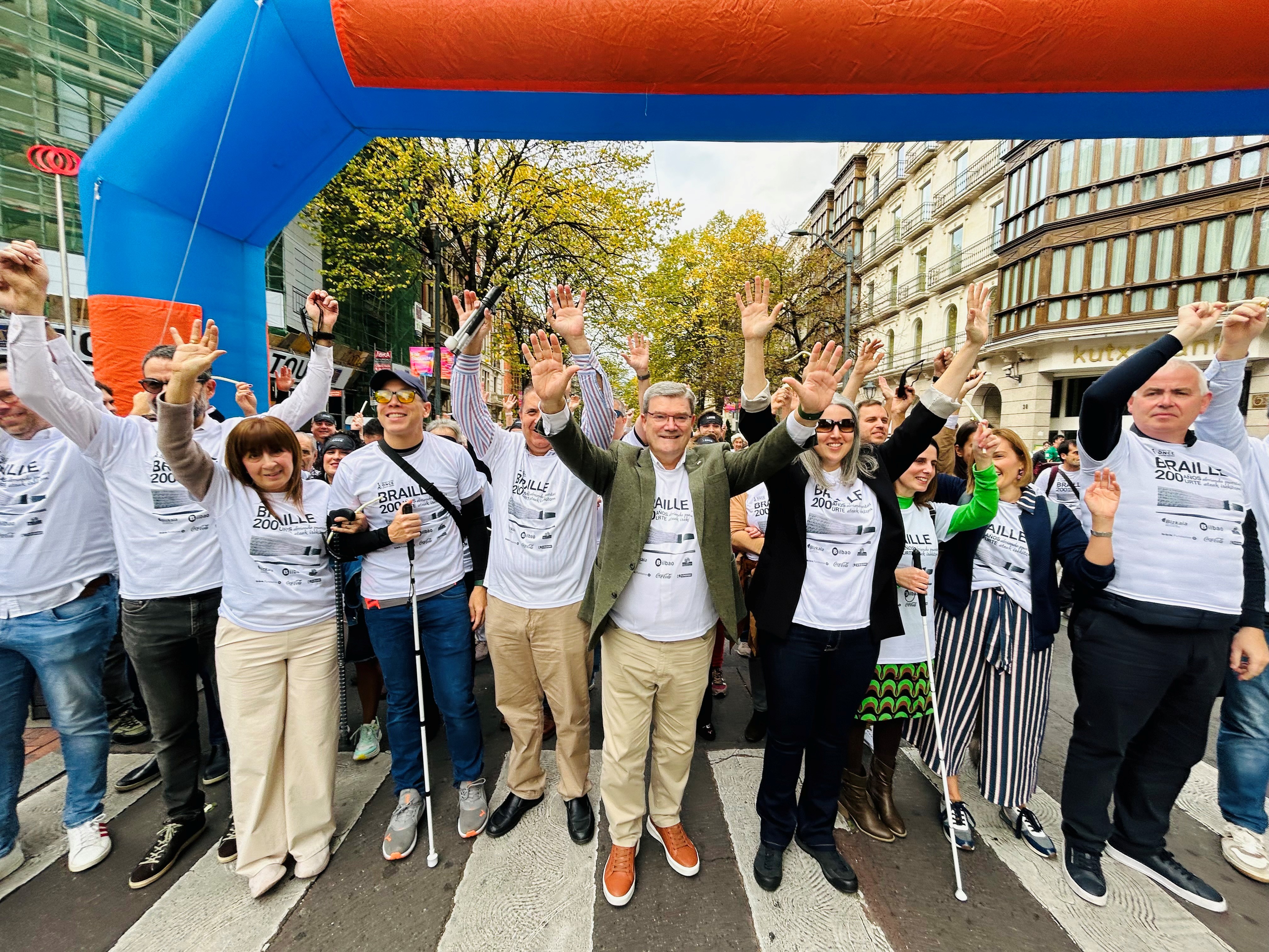 Cabecera de participantes en la carrera antes de la salida alzando las manos