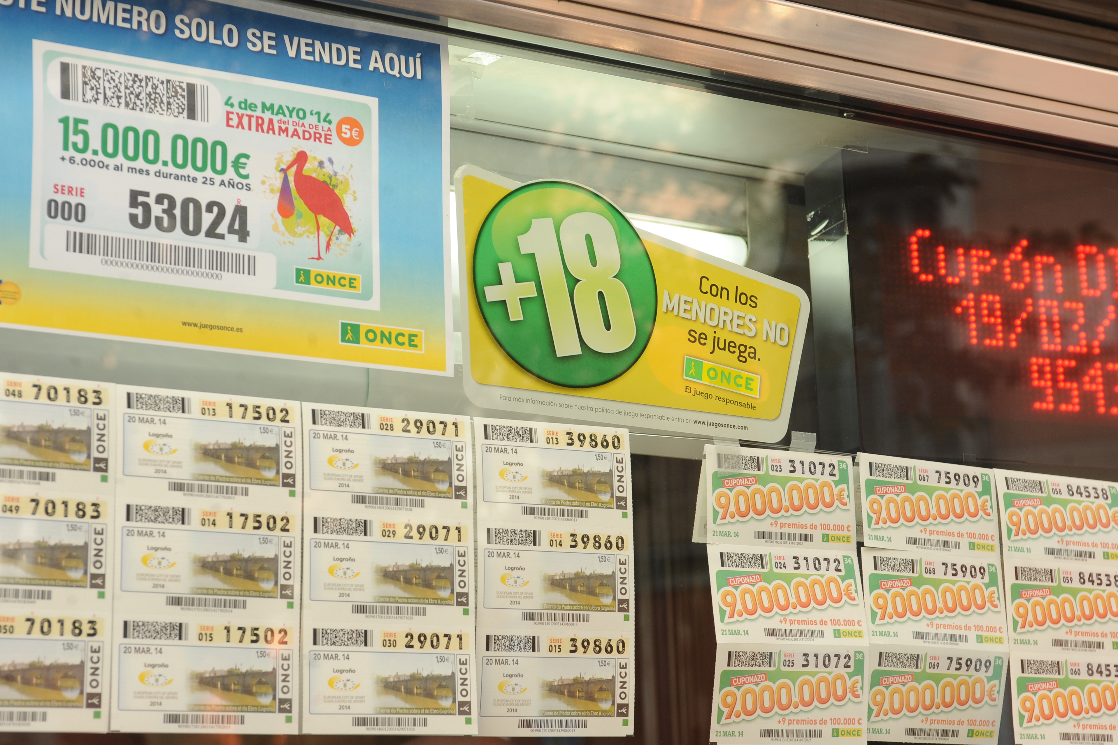 Primer plano del escaparte de un quiosco de la ONCE con los cupones expuestos y un vinilo alertando de que no se vende juego a menores de 18 años
