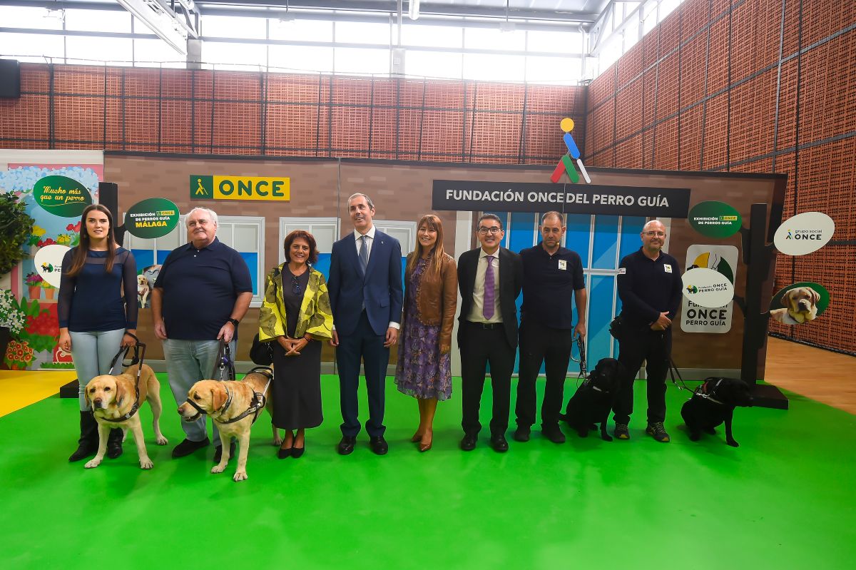 Foto de familia de las autoridades, instructores y usuarios de perros guía participantes en la exhibición de Málaga