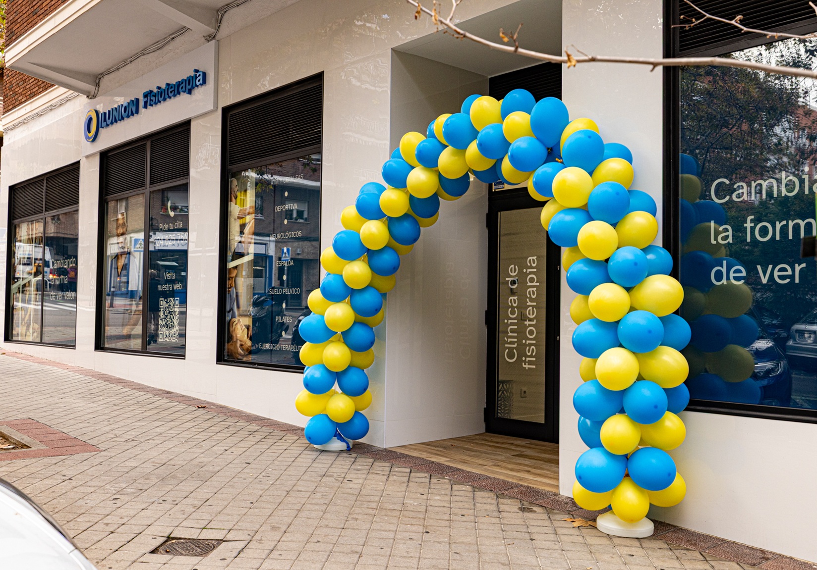 Fachada de la clinica de Ilunion en la calle Pensamiento, con la puerta de acceso adornada con globos azules y amarillos, colores corporativos de ILUNION