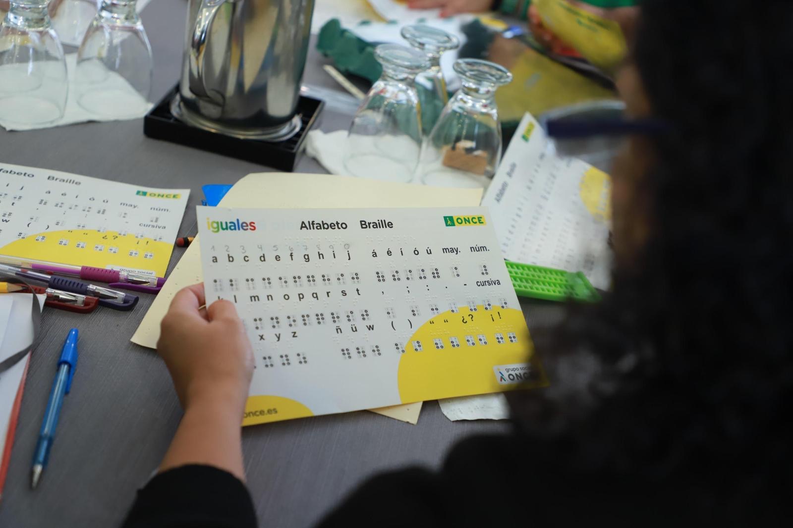 Una de las profesionales docentes participantes en curso muestra el alfabeto braille de la ONCE 