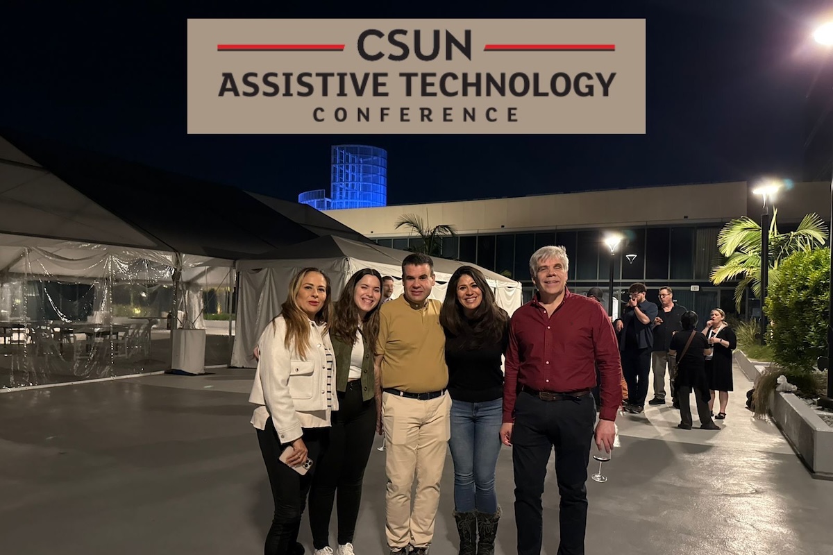 Foto de grupo con los 3 participantes de ONCE y dos compañeras de México delante de un edificio iluminado en azul. Arriba logo de CSUN Assistive Technology Conference.