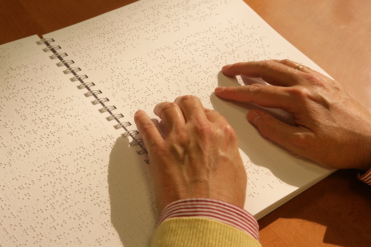 Las manos de una persona ciega leen un libro en braille Las manos de una persona ciega leen un libro en braille