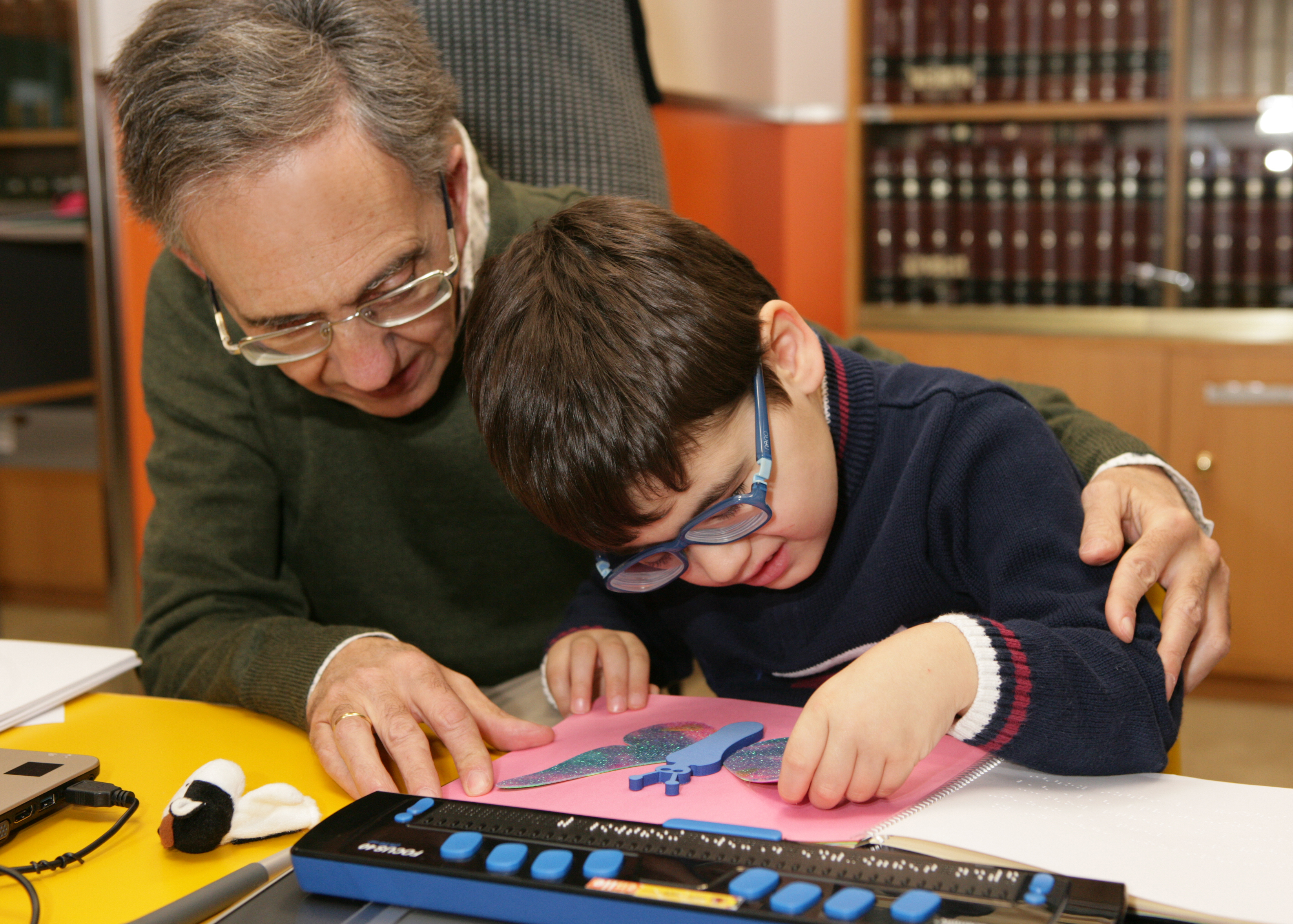 Profesor de la ONCE junto a un niño afiliado en un aula