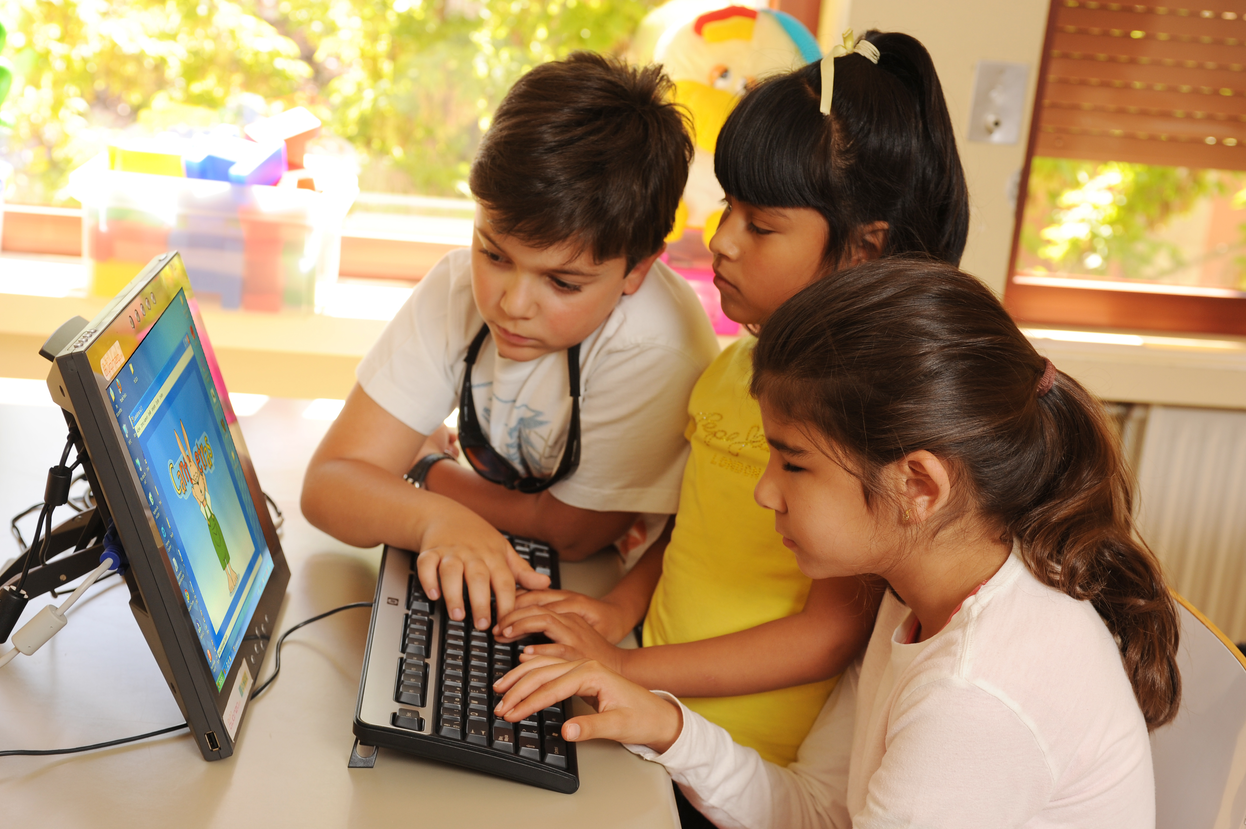 Tres niños y niñas con y sin discapacidad visual manejan un juego adaptado