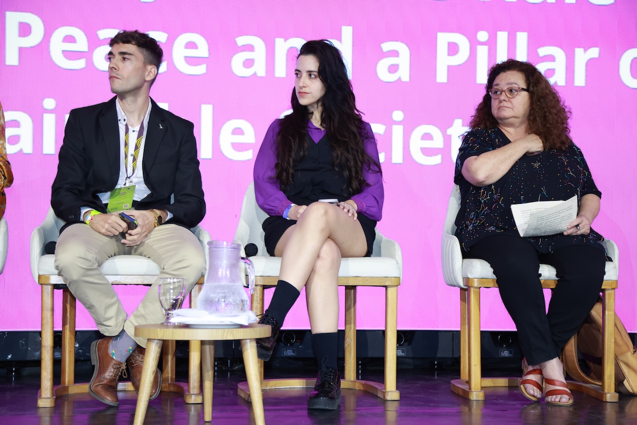 Primer plano de varios ponentes sentados, mirando con atención