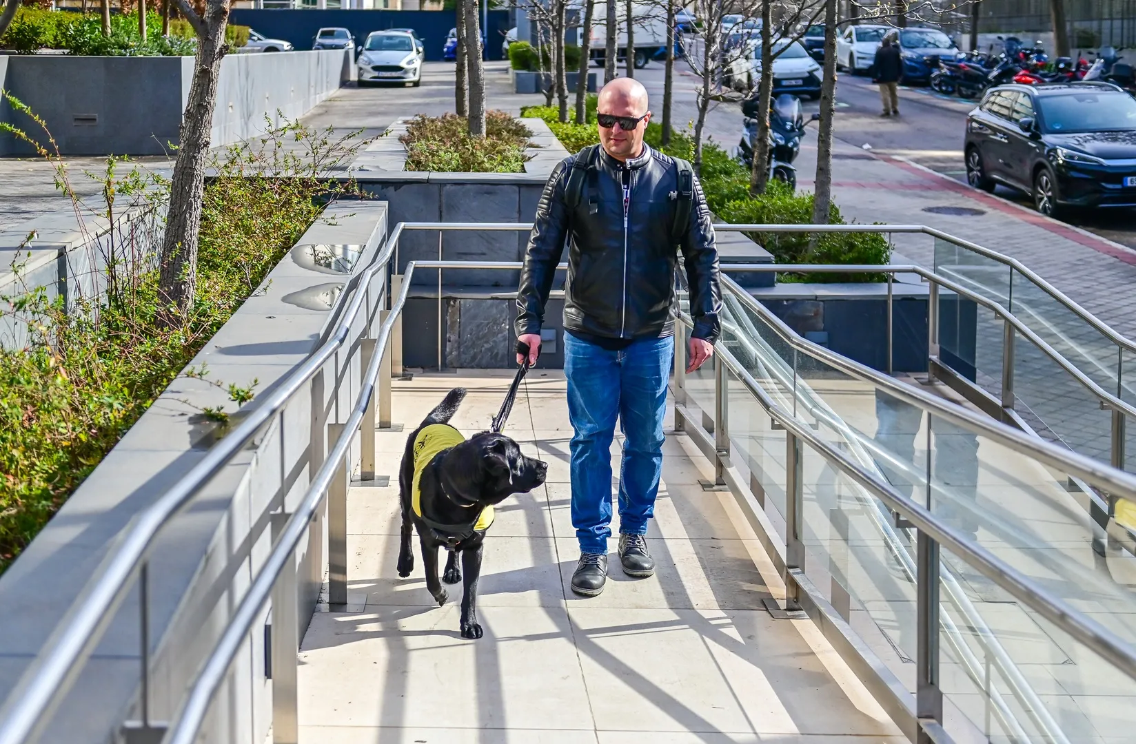 Persona ciega con su perro guía accede por una rampa a un hotel Ilunion