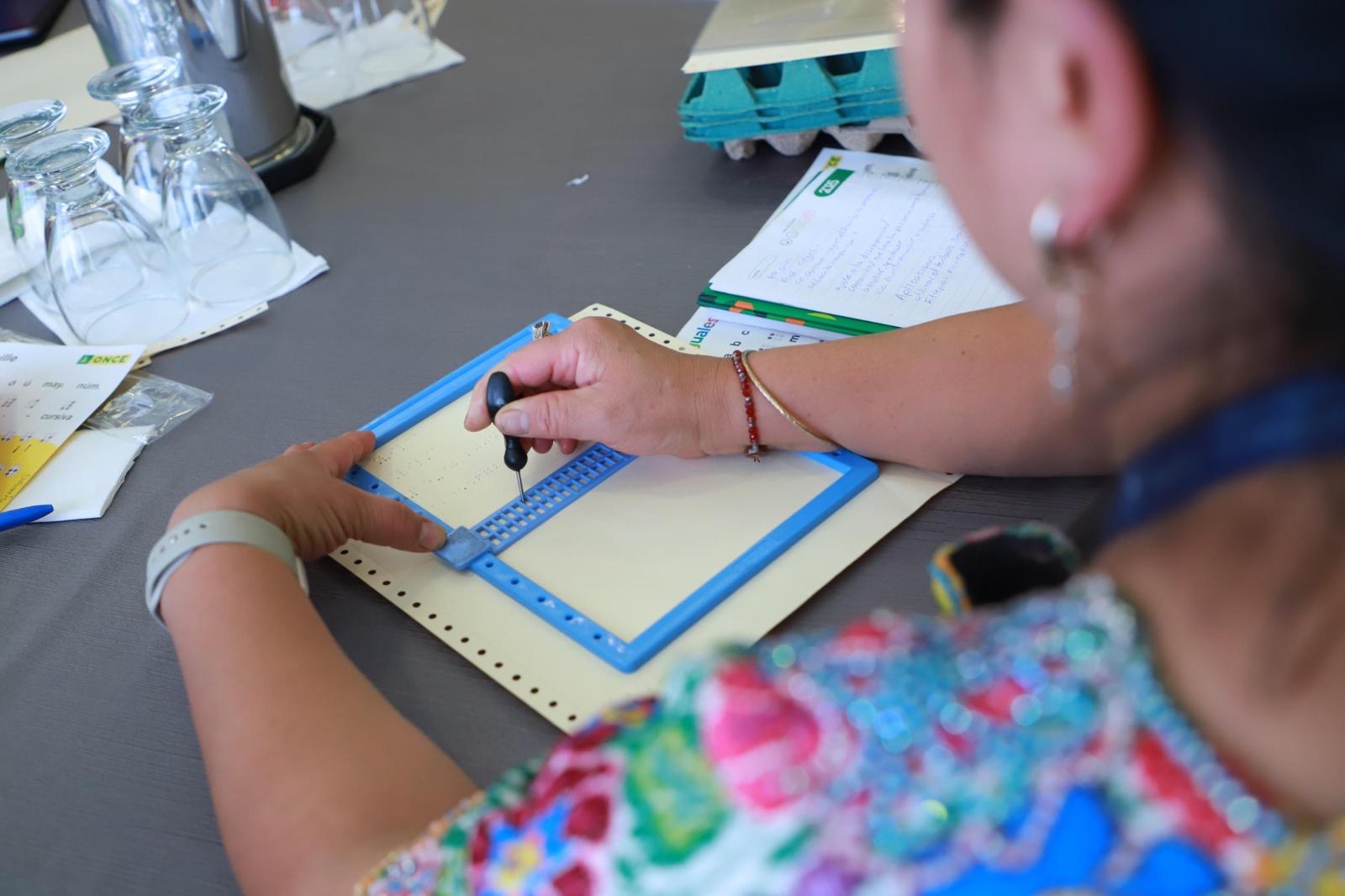 Otra docente participante en curso escribe en braille con la ayuda de una regleta y un punzón