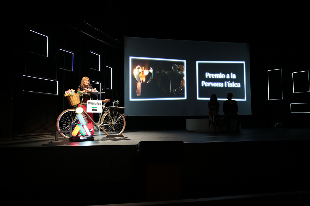 Isabel Roldán recogiendo el Premio a la Persona Física y hablando desde el atril del escenario