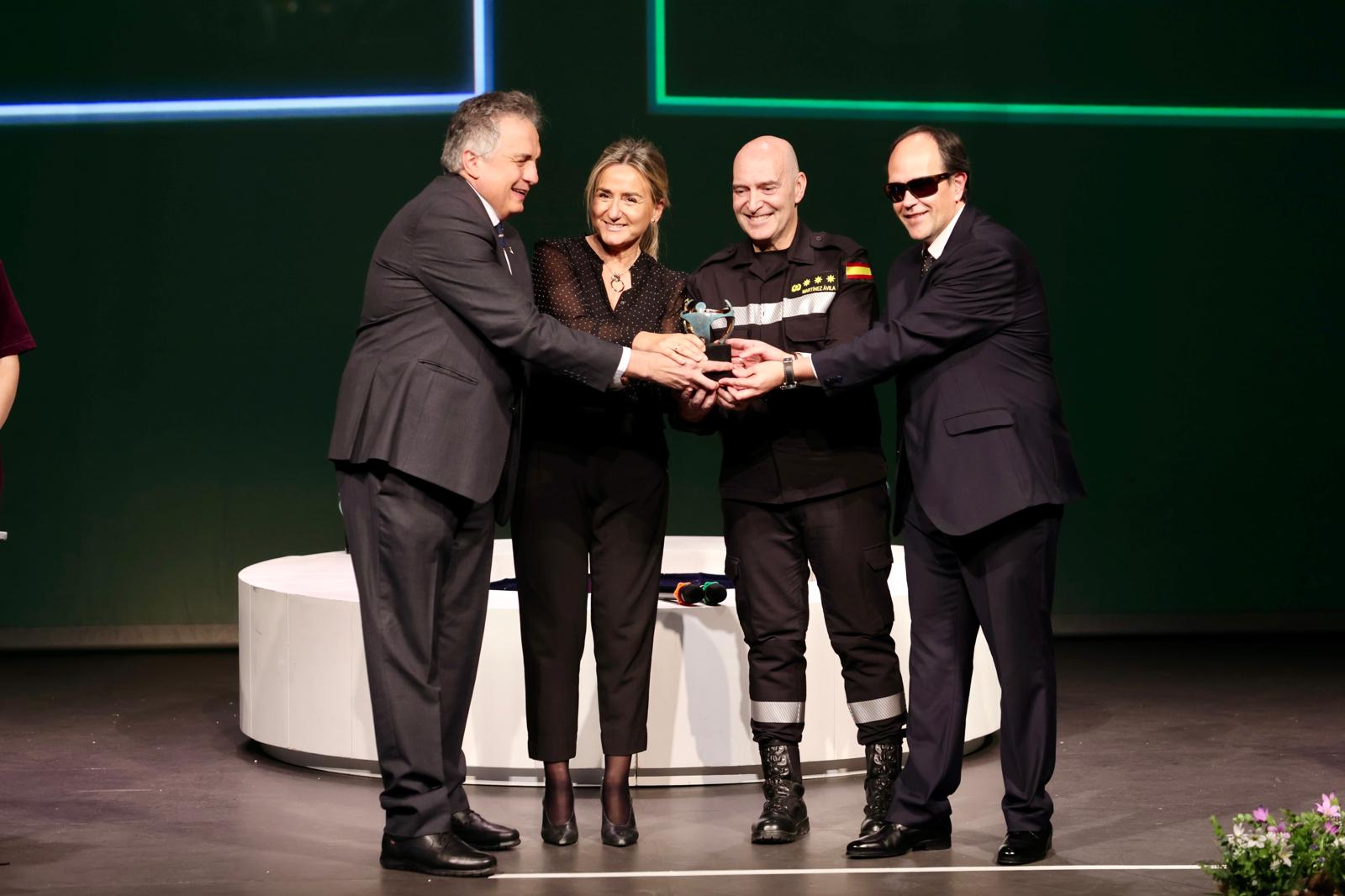Los premiados sonrientes y tocando todos el trofeo